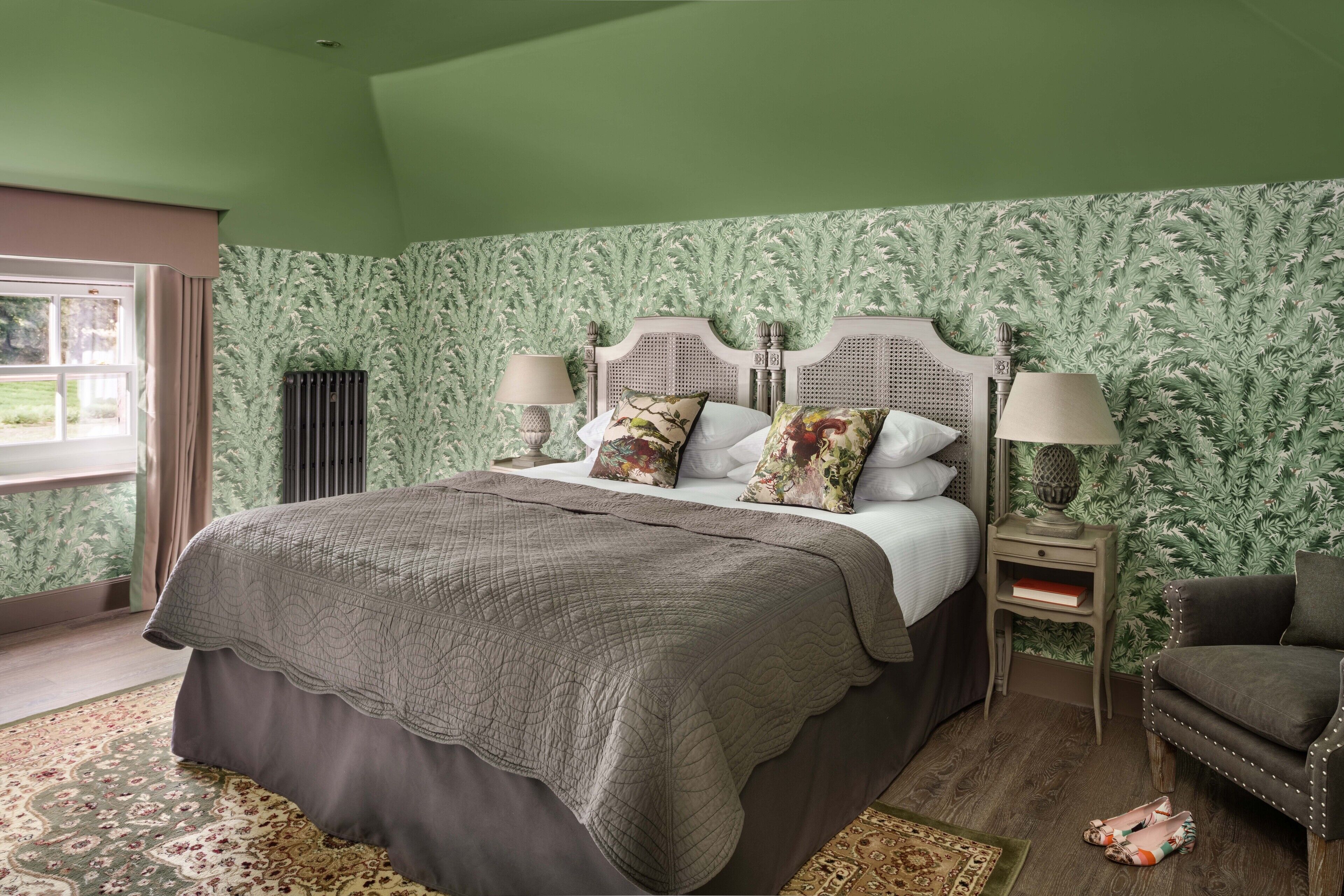 A bedroom with a large bed, a nightstand, a chair, and a window.