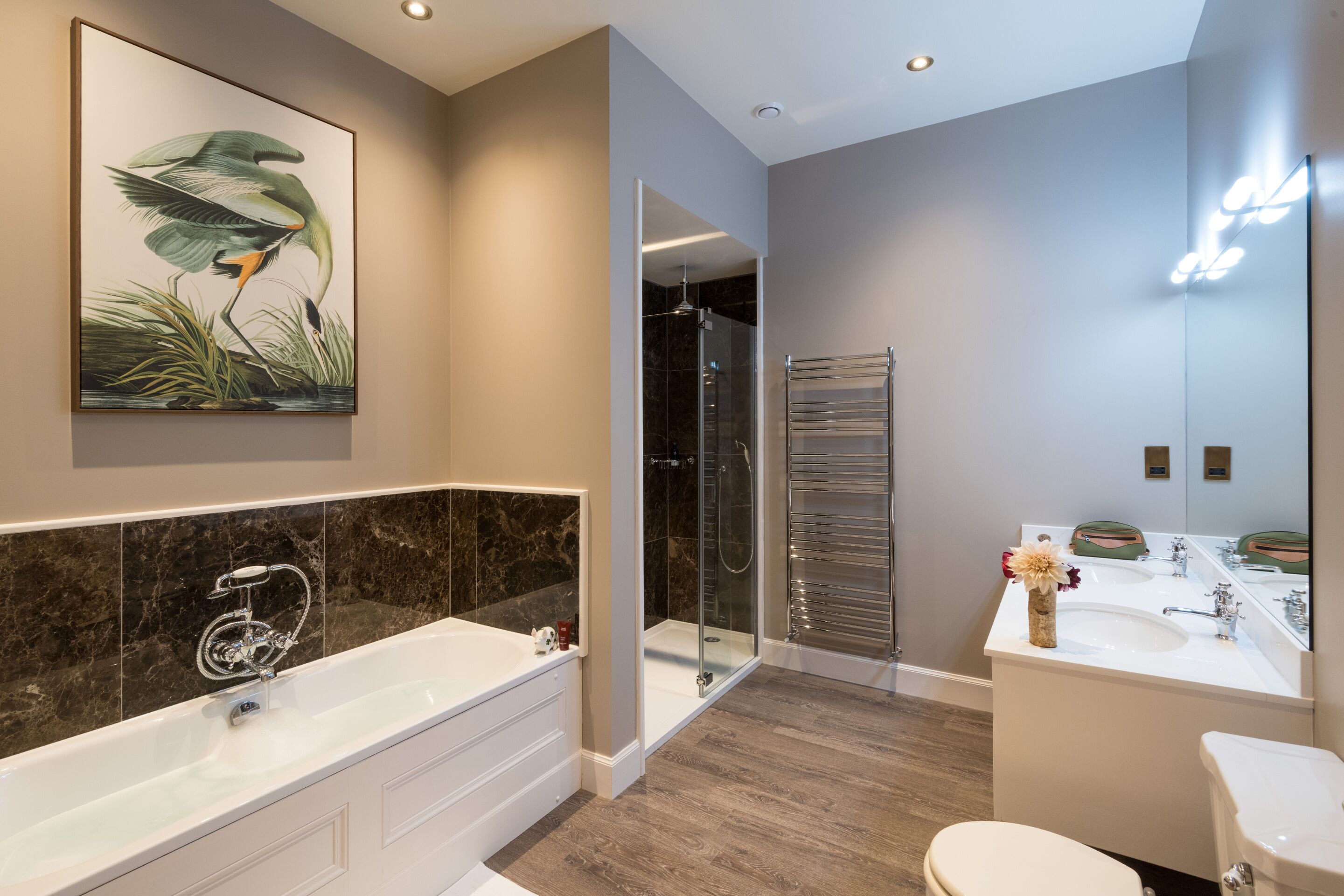 Une salle de bain moderne dotée d’une grande baignoire, d’une douche à parois de verre et d’un meuble-lavabo avec un miroir.