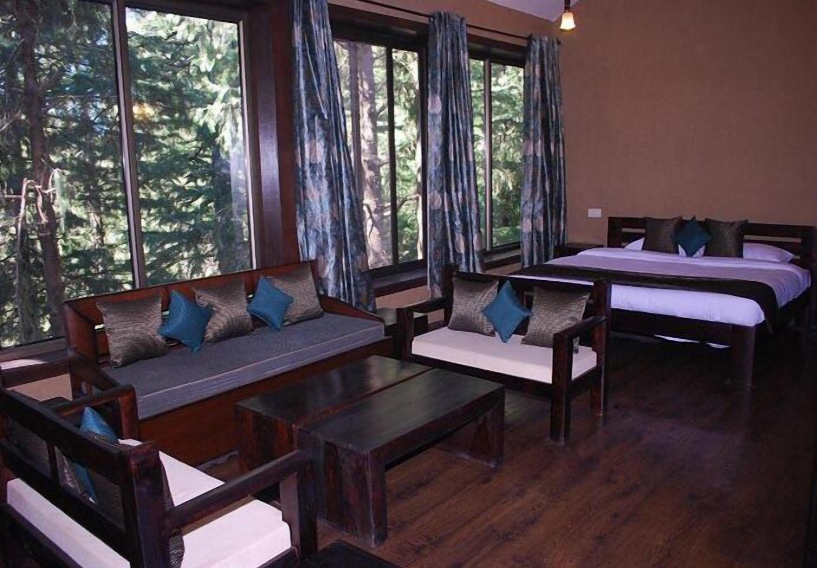 A room with a sofa, a bed, and a window with curtains.