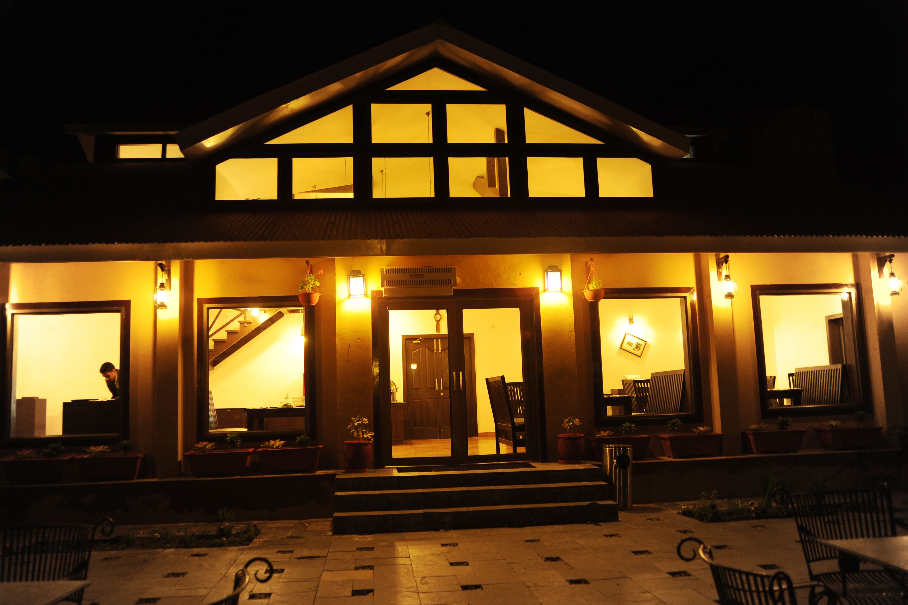 A hotel with a central entrance, multiple windows, and outdoor seating.
