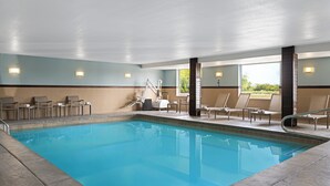An indoor swimming pool with lounge chairs and a view of greenery outside. - Holiday Inn Express Toledo North by IHG (Toledo)