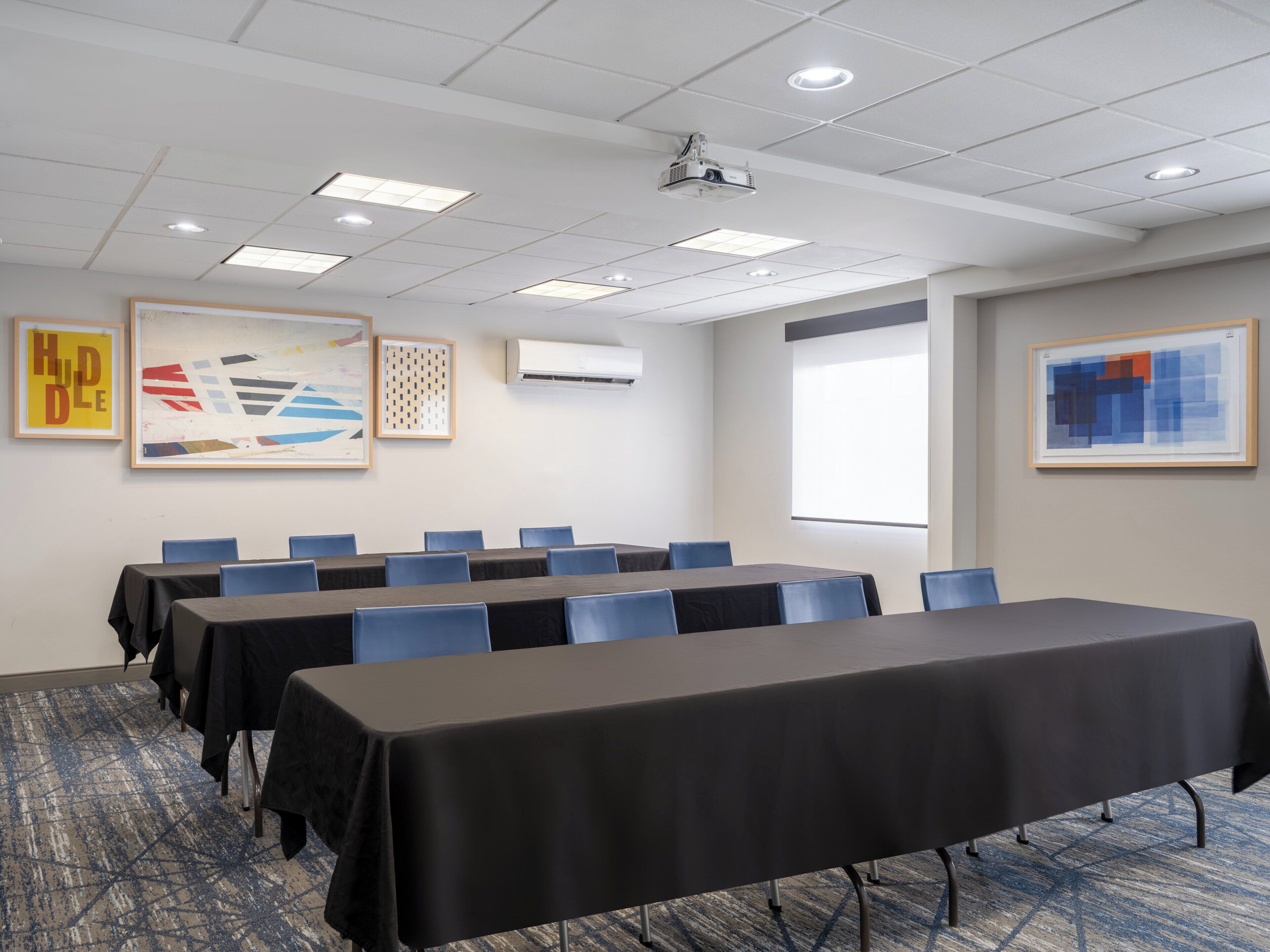 A conference room with tables, chairs, and ceiling lights.