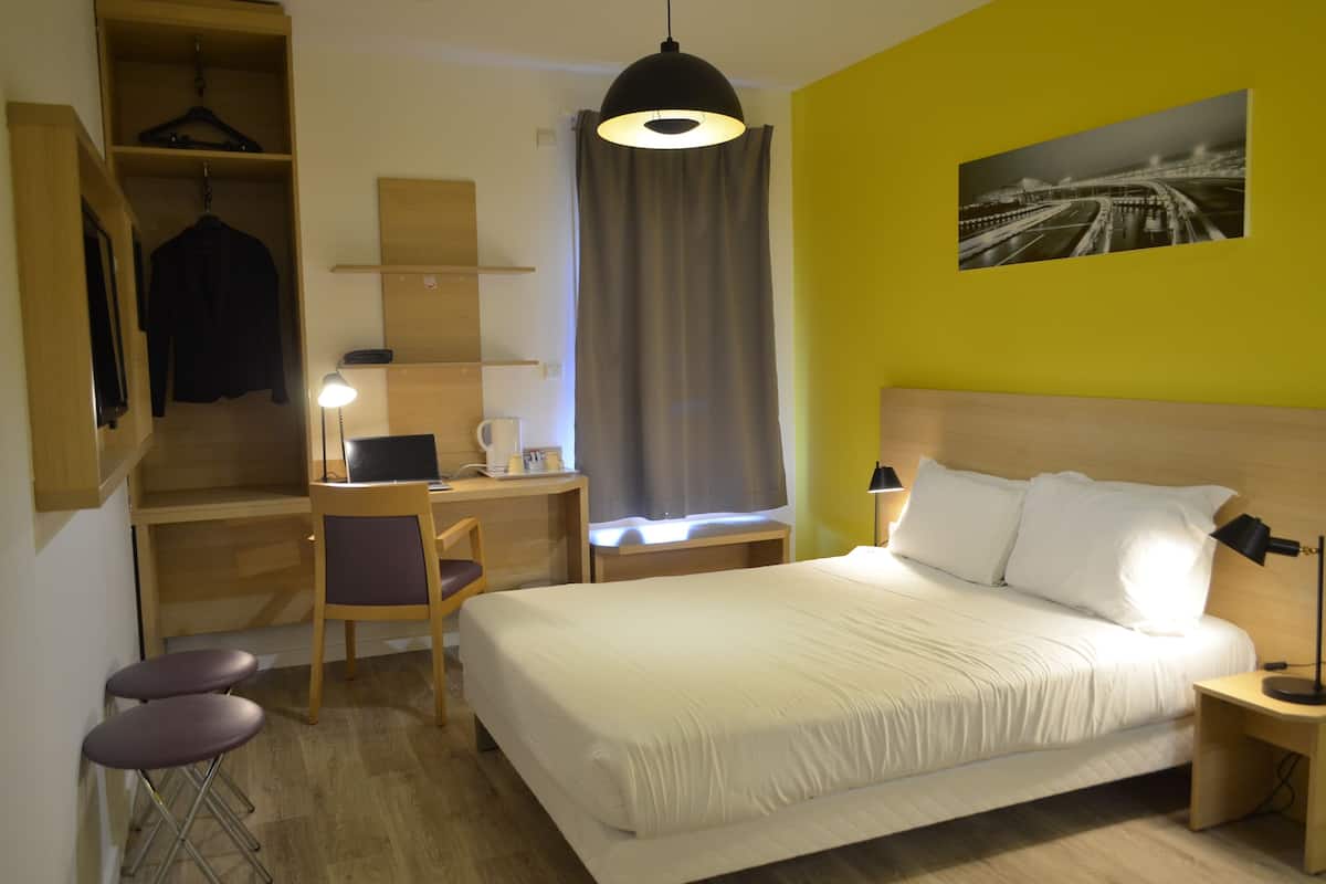 Une chambre d’hôtel équipée d’un lit, d’un bureau, d’une chaise et d’un porte-manteau mural.