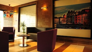 Eine Hotelhalle mit Rezeption, Sitzgelegenheiten und einem großen Stadtbild.
