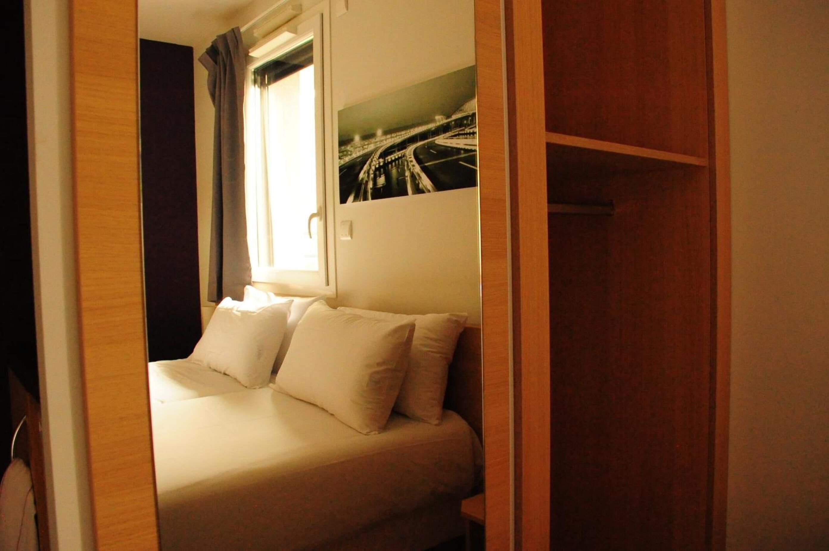 Une chambre à coucher avec un lit, une fenêtre avec des rideaux et un tableau accroché au mur.