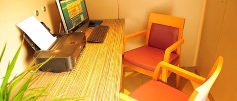 A room with a bamboo-textured desk, a laptop, a desktop computer, and a colorful chair.