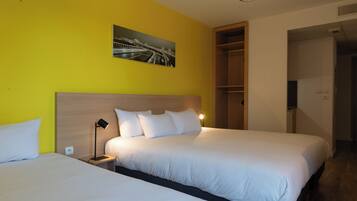 A hotel room with two beds, a wooden headboard, a nightstand with a lamp, a painting on the wall, and a built-in closet.