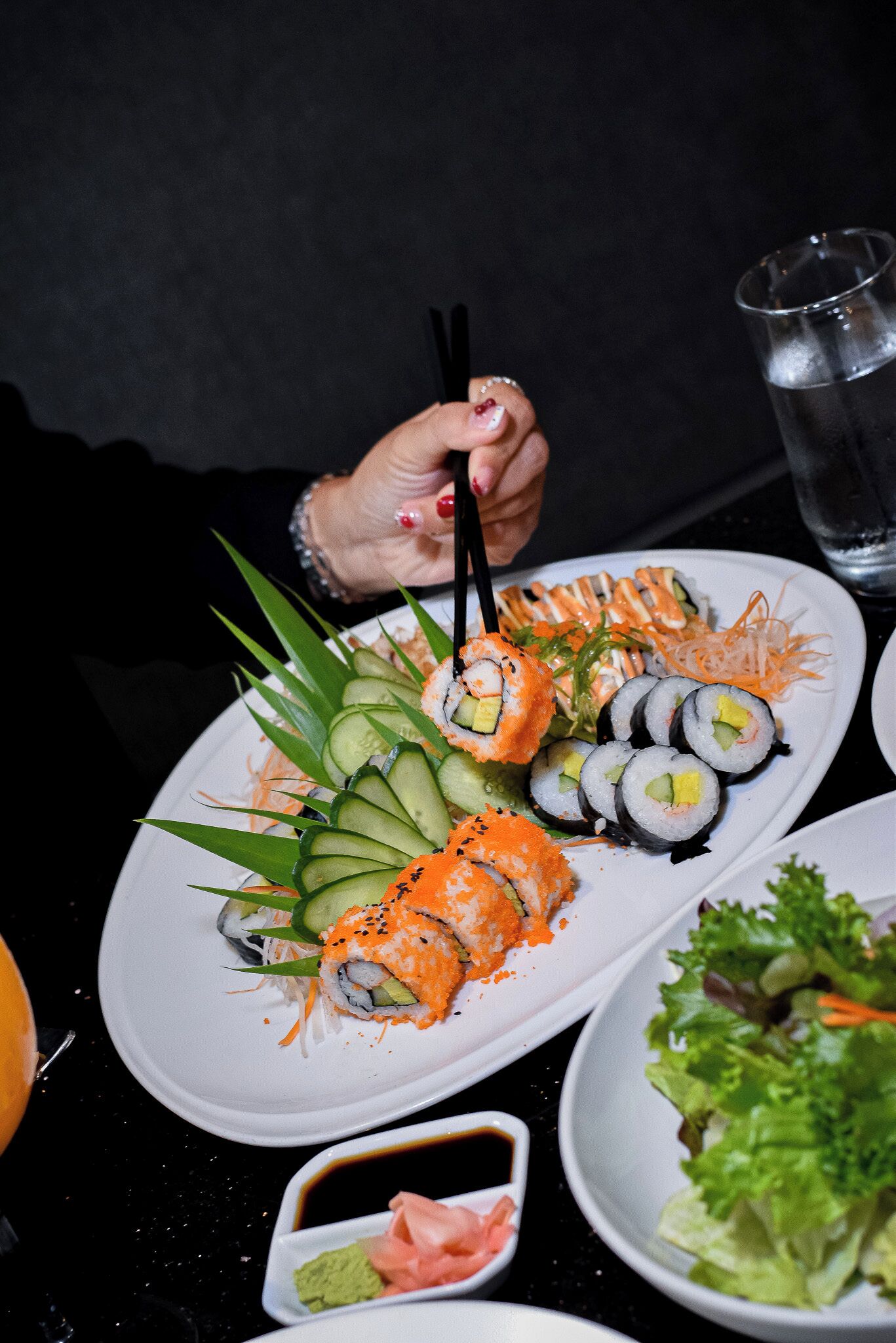 A plate of sushi with various toppings and a small dish of sauce.