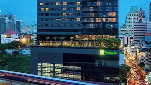 A modern high-rise building with multiple floors, featuring a Holiday Inn sign at the base. - Holiday Inn Bangkok Sukhumvit by IHG (Bangkok)