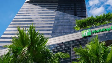 A Holiday Inn hotel with a modern glass facade and palm trees in the foreground.