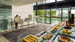 A buffet setup with various food items and a bartender preparing drinks. - Holiday Inn Bangkok Sukhumvit by IHG (Bangkok)