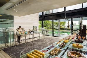 A buffet setup with various food items and a bartender preparing drinks. - Holiday Inn Bangkok Sukhumvit by IHG (Bangkok)