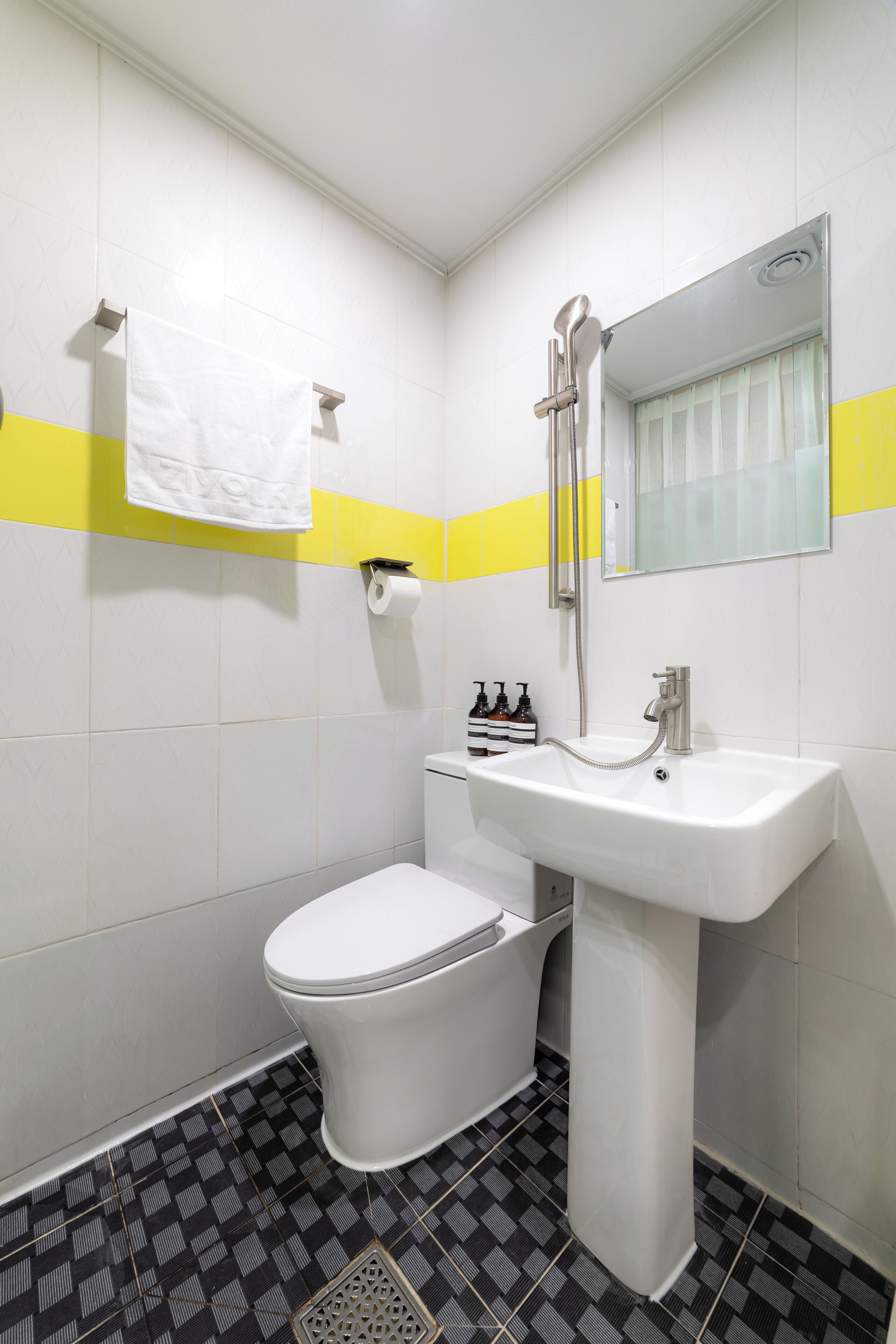 A bathroom with a toilet, sink, and mirror.