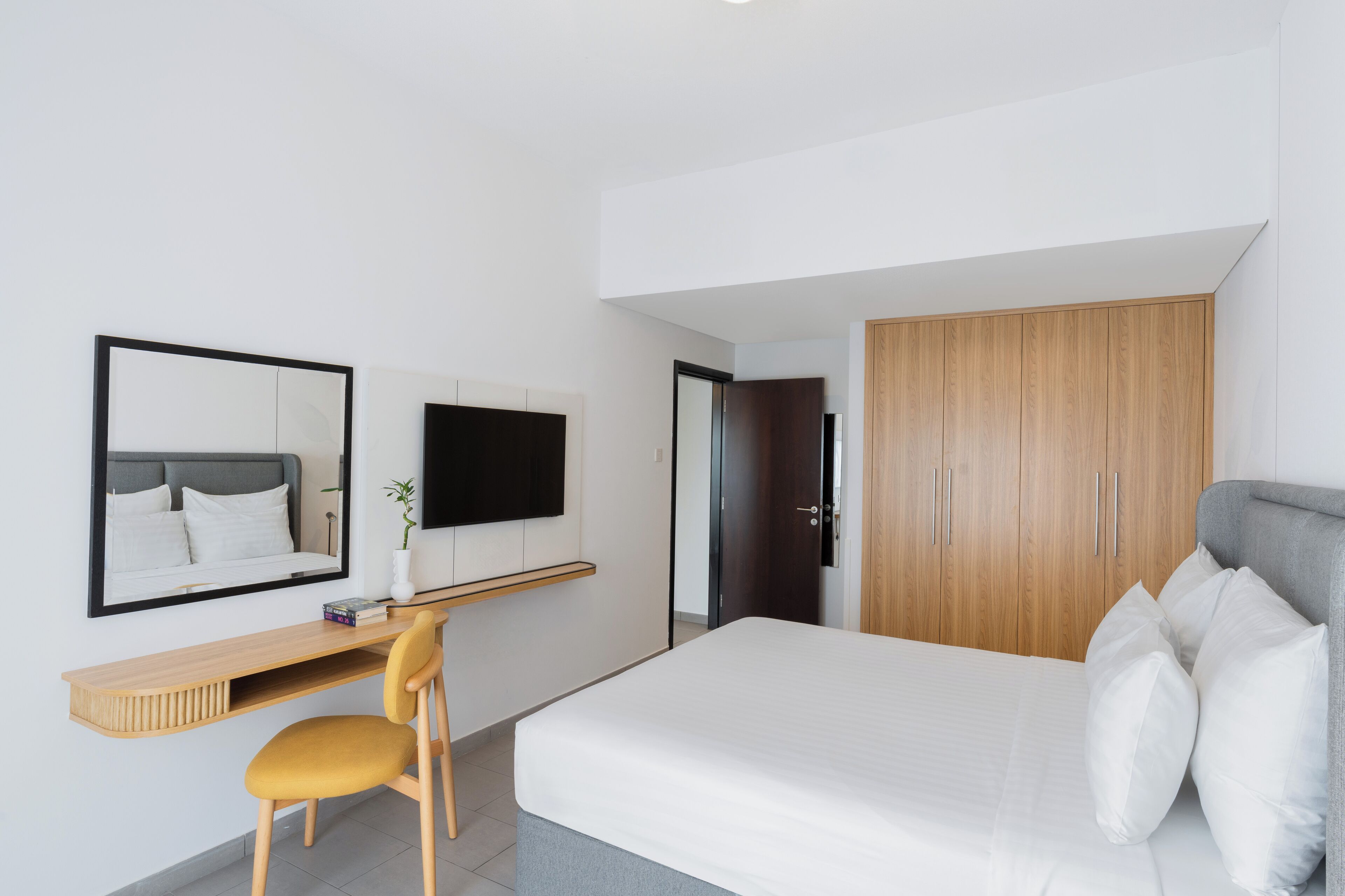 Een moderne slaapkamer met een bed, een bureau, een stoel en een garderobe.