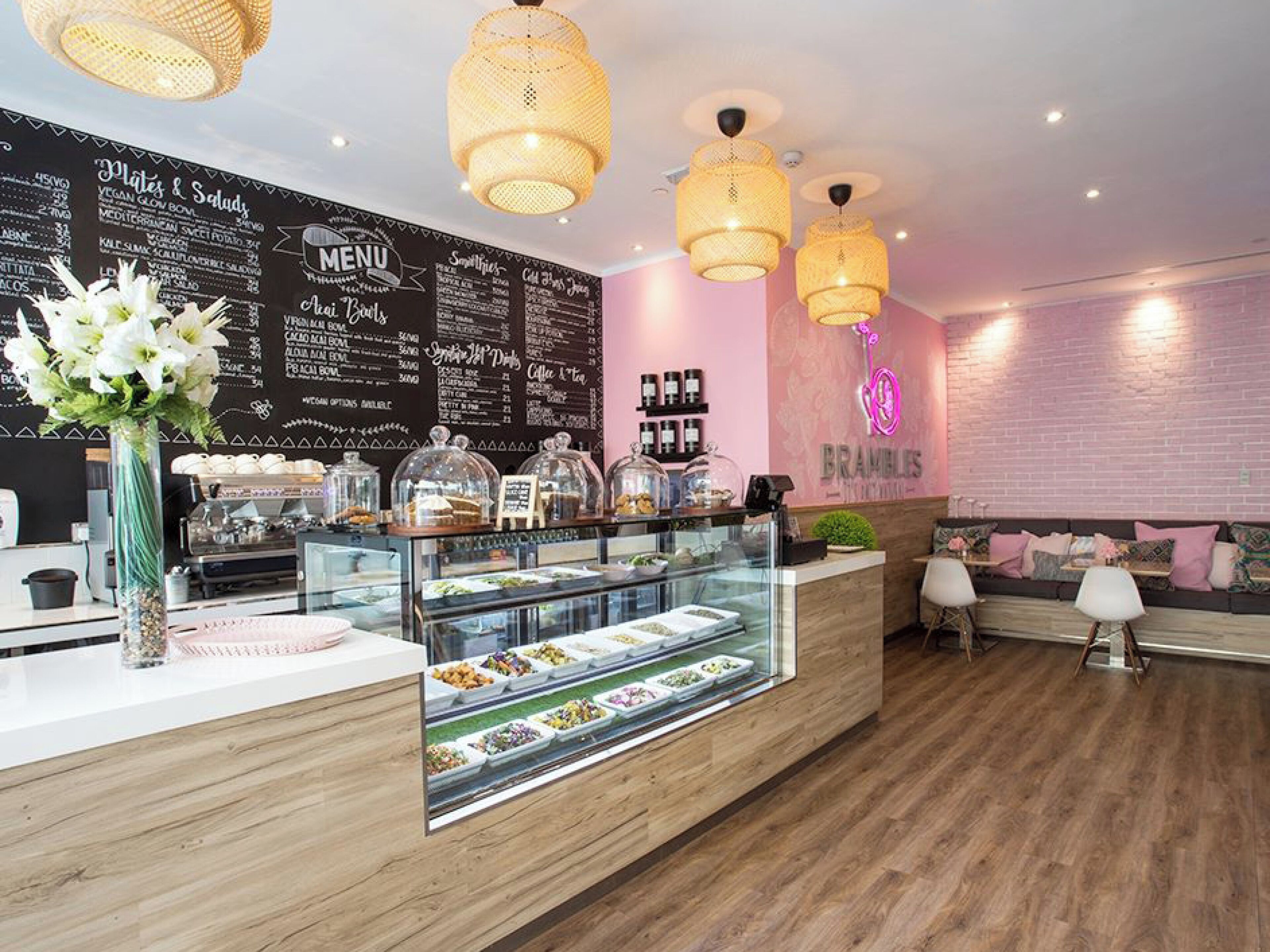 A cafe with a wooden counter, a menu board, and hanging lights.