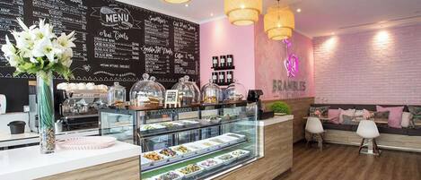 A cafe with a wooden counter, a menu board, and hanging lights.