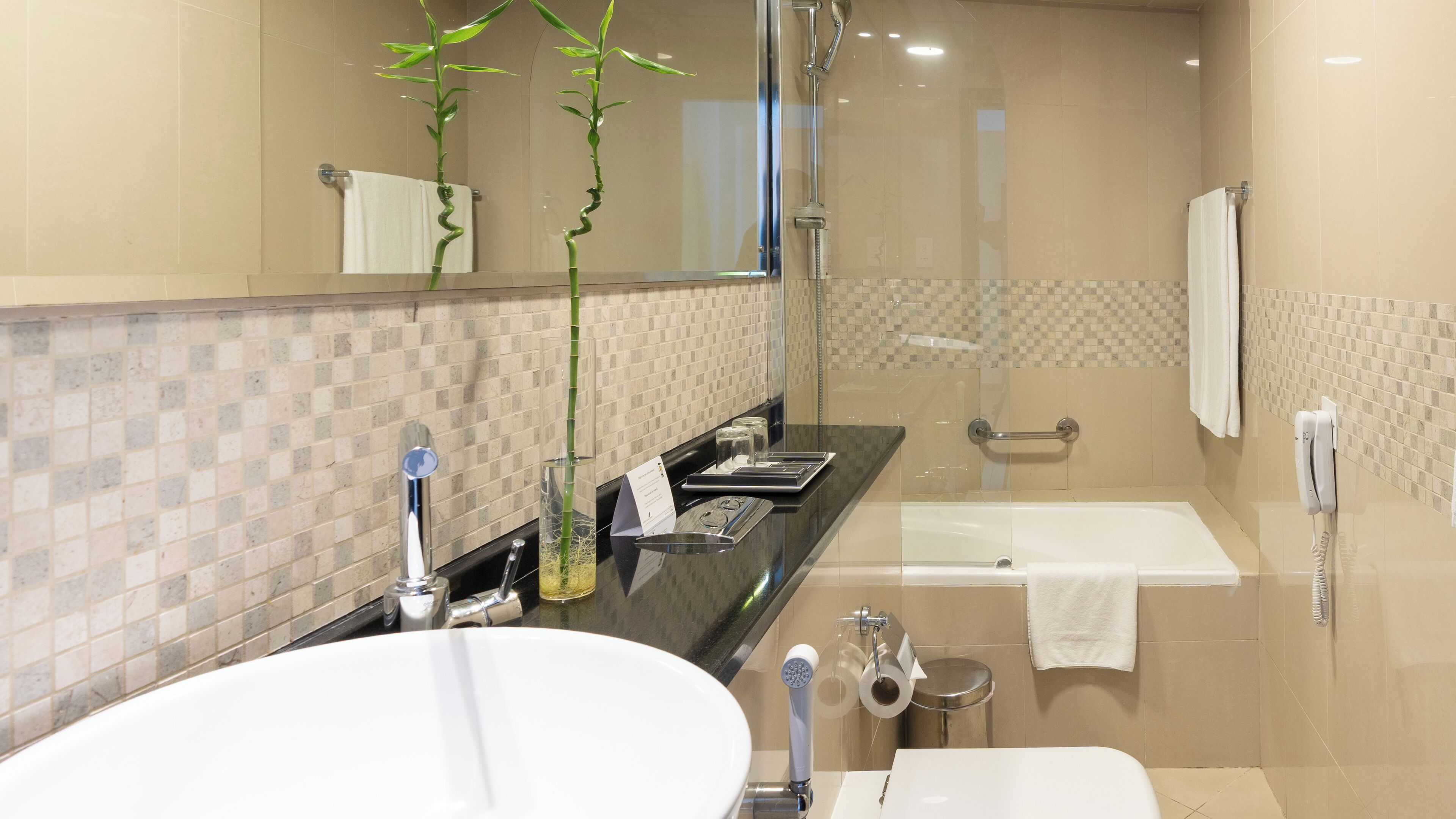 A modern bathroom with a large mirror, a sink, a bathtub, and a shower.