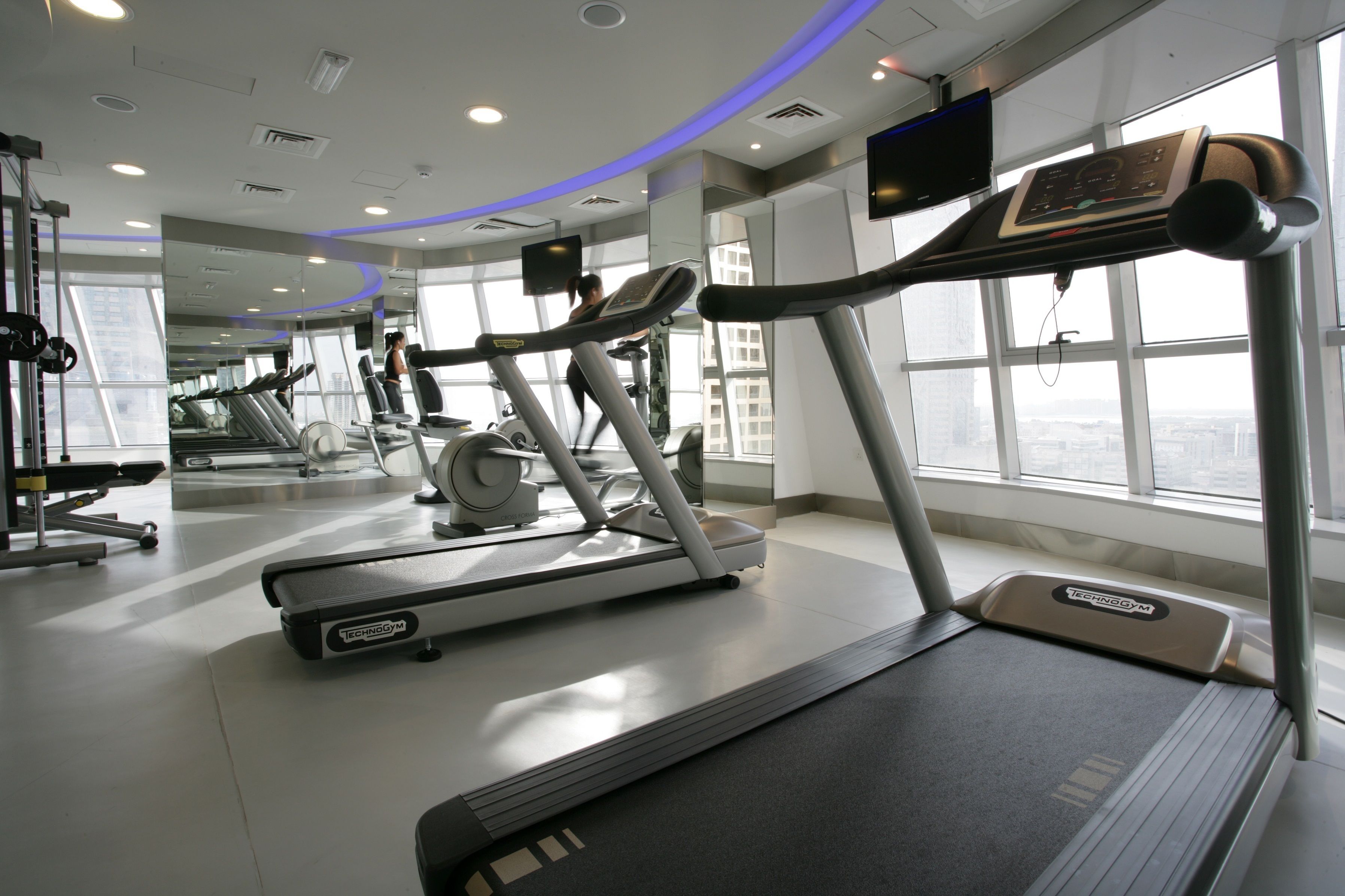 Une salle de sport équipée de tapis de course, de vélos d’exercice et d’appareils de musculation.