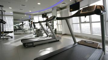 Une salle de sport équipée de tapis de course, de vélos d’exercice et d’appareils de musculation.