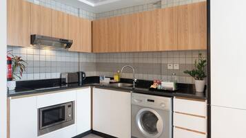 A compact kitchen with a microwave, toaster, sink, and built-in washing machine.