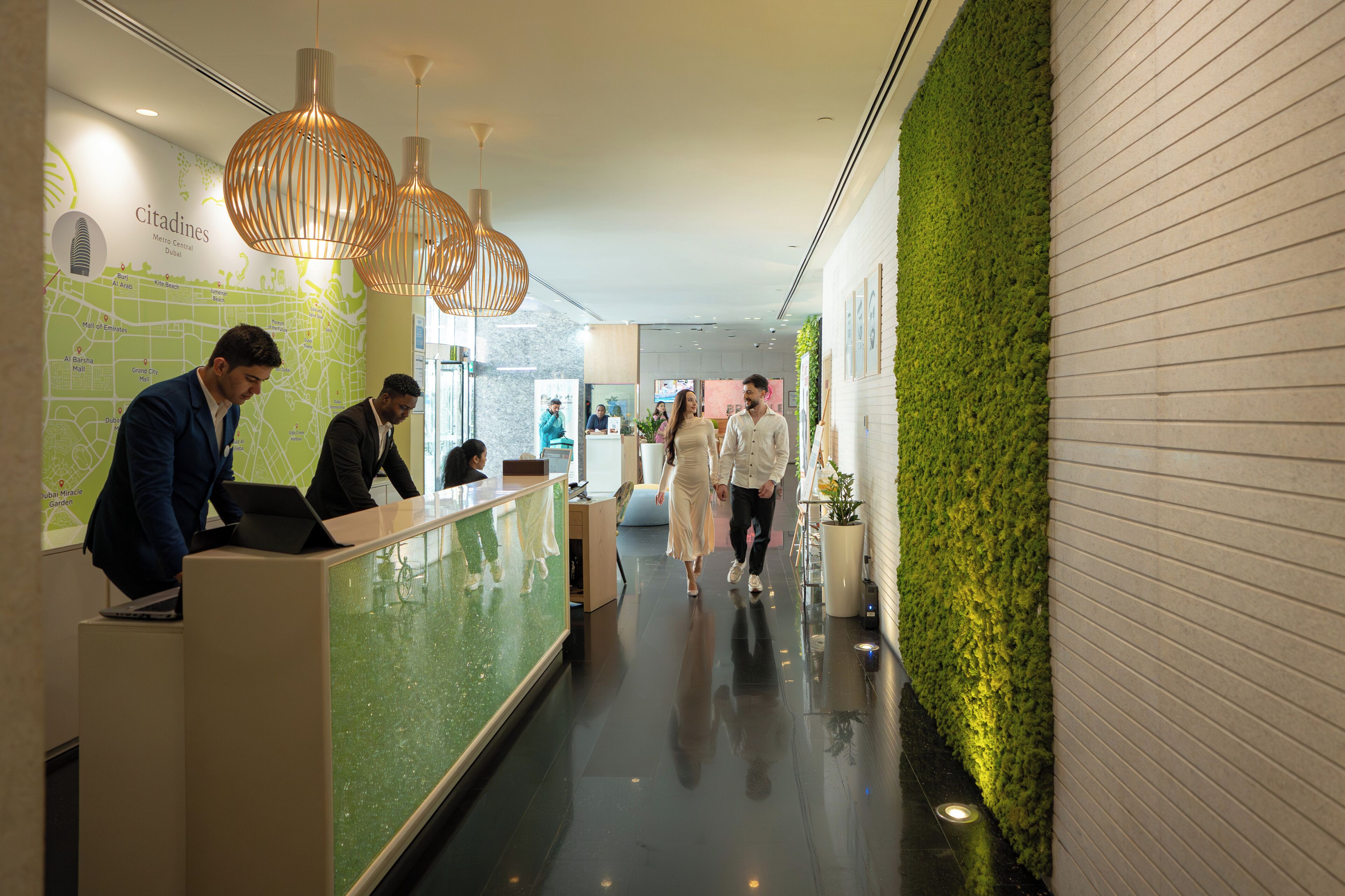 A hotel reception area with a map, reception desk, and a green wall.