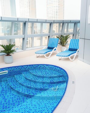 Una piscina al aire libre, sillones reclinables de piscina