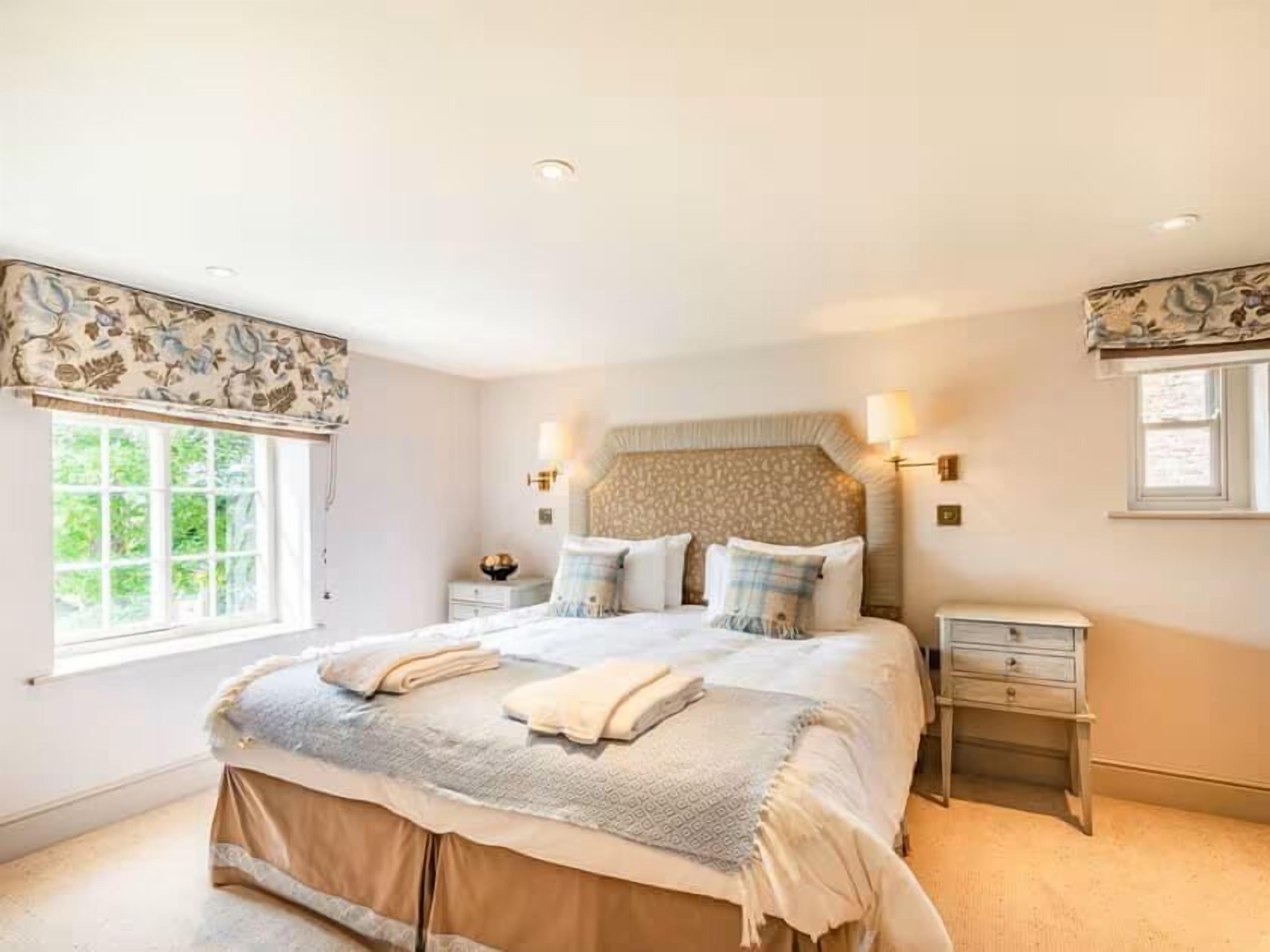 A bedroom with a large bed, bedside tables, and a window with curtains.