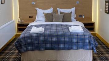 A neatly made bed with a blue and white polka dot bedspread, two pillows, and two folded towels.