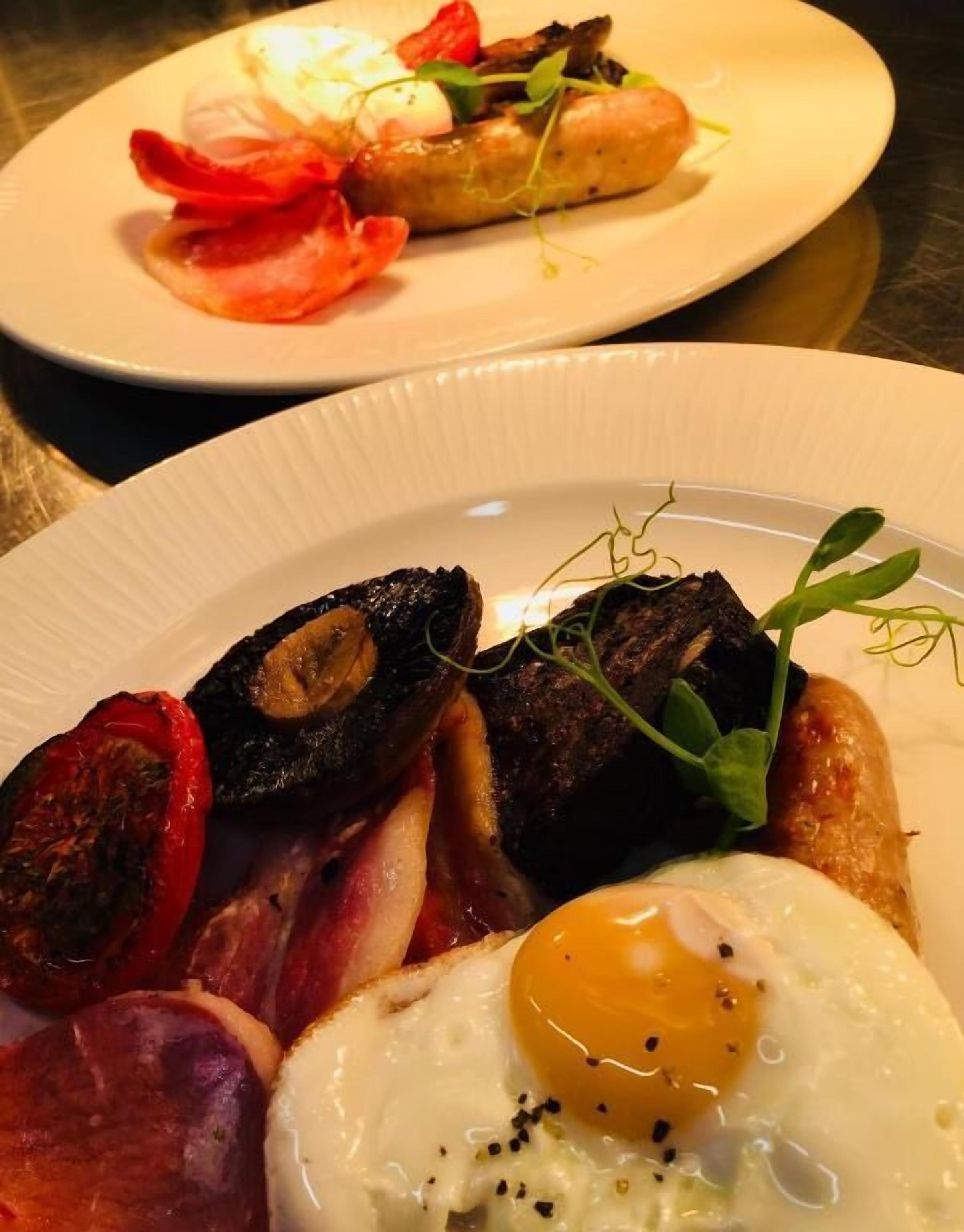 A breakfast plate with eggs, bacon, mushrooms, and tomatoes.