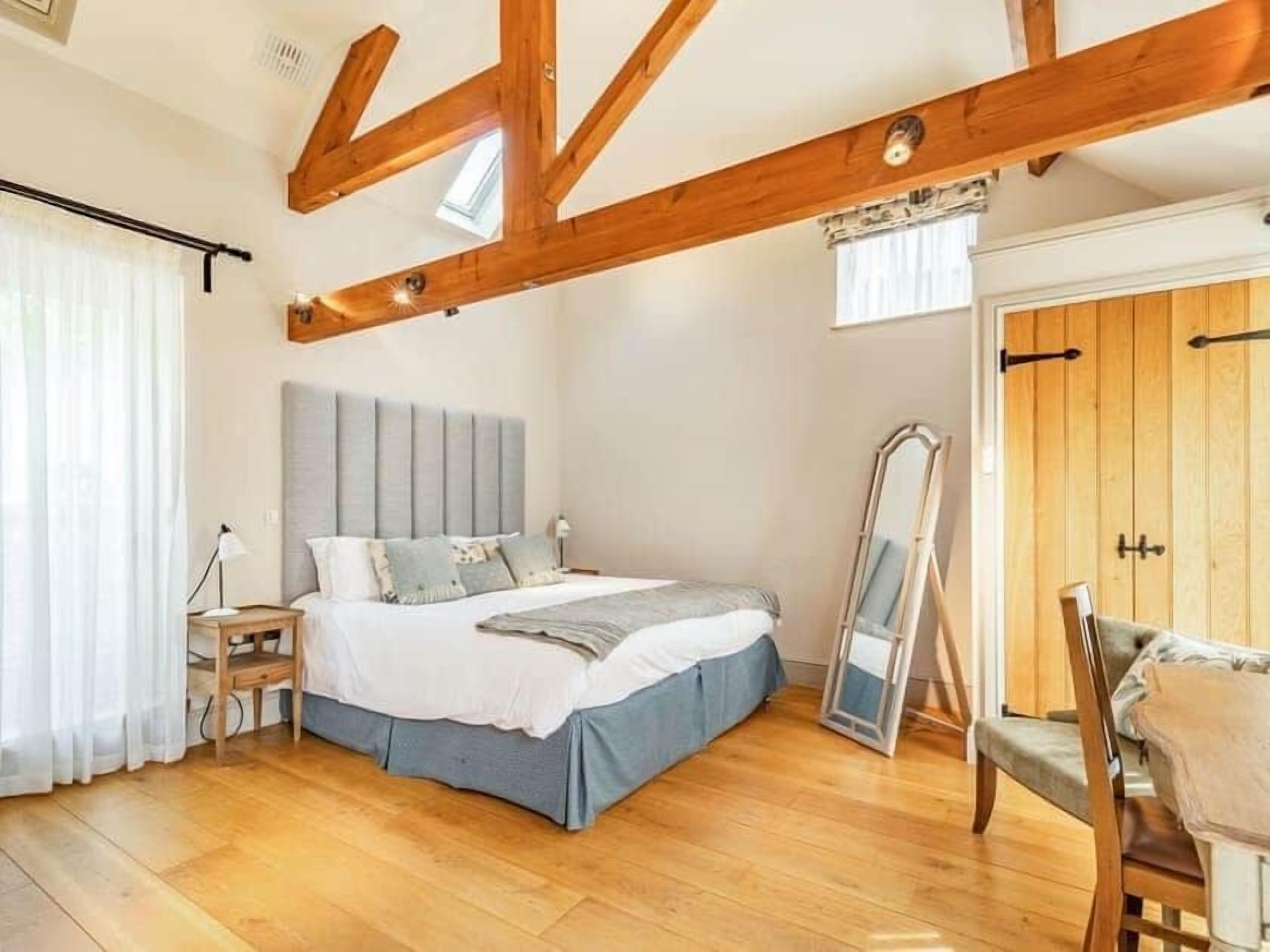 A bedroom with a bed, wooden beams, a window, and a door.