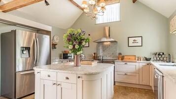 Una cocina con isla central, electrodomésticos de acero inoxidable y una lámpara decorativa.