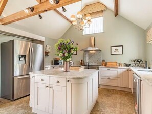 A kitchen with a central island, stainless steel appliances, and a decorative light fixture. - The Carpenters Arms  (Thirsk)