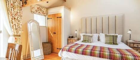 Een slaapkamer met een groot bed, houten balken, een kledingkast en een spiegel.