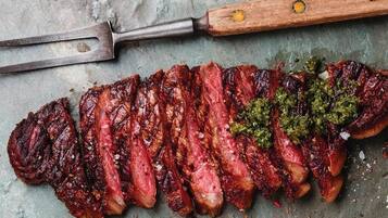 Un steak, une fourchette à viande en bois et une spatule en métal, le tout posé sur une surface texturée.
