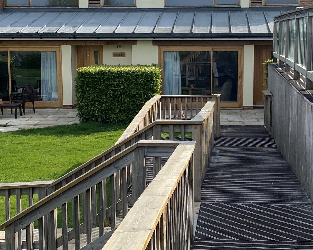 A hotel with a covered outdoor area, a wooden deck, and a grassy lawn.