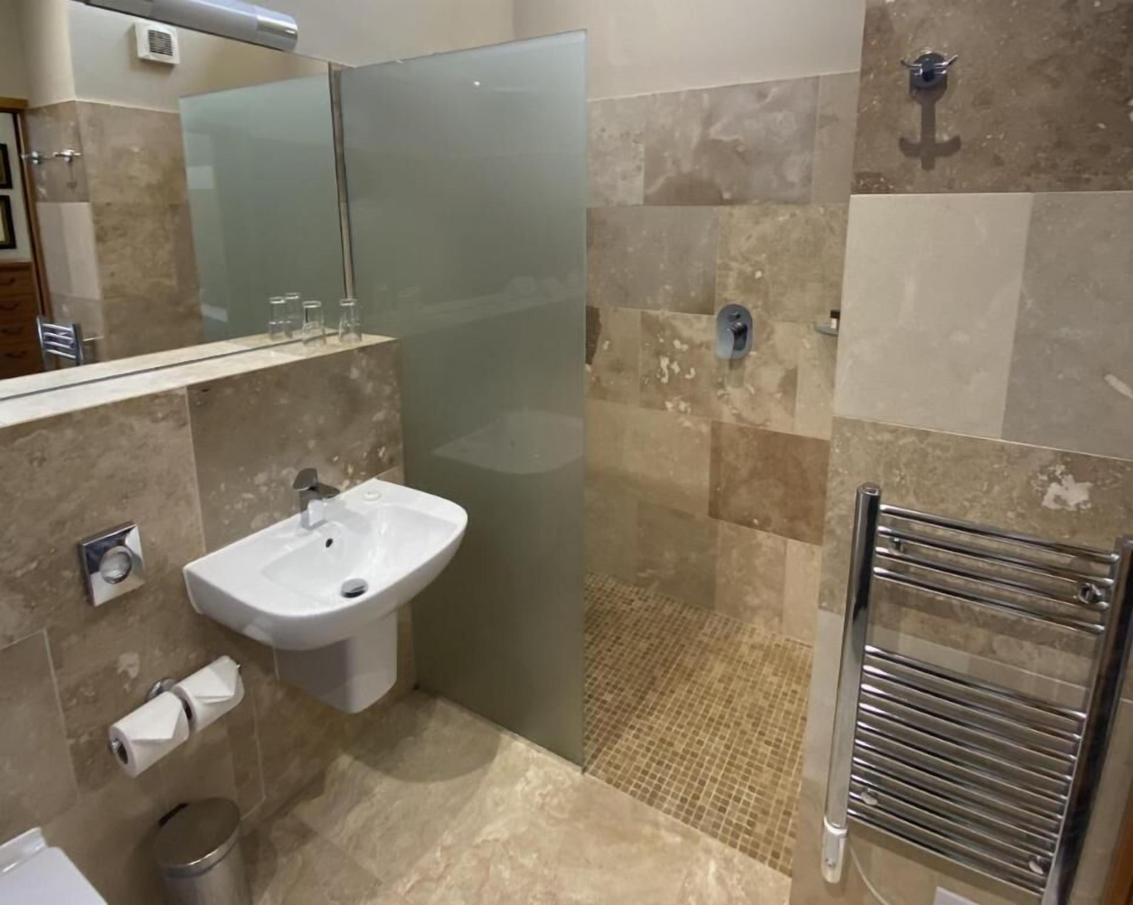 Un baño moderno con cabina de ducha de vidrio, un lavamanos y un perchero para toallas.
