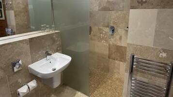 A modern bathroom with a glass shower enclosure, a sink, and a towel rack.