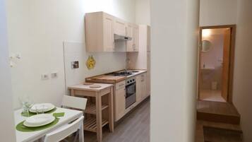 A compact kitchen with a dining area, wooden cabinets, a stove, and a small table with chairs.