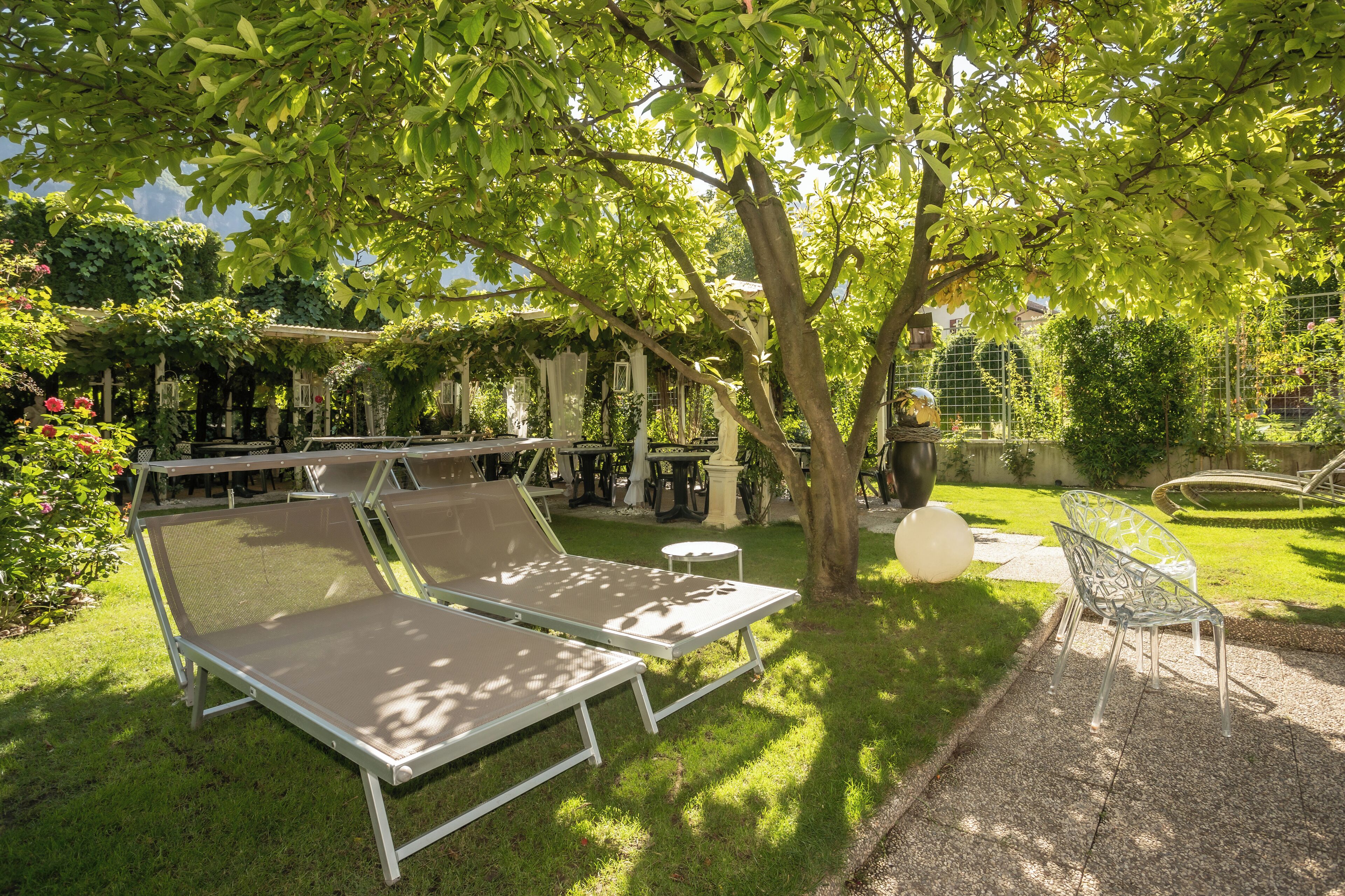 Ein Garten mit zwei Liegestühlen, einem kleinen runden Tisch und einem Metallstuhl.