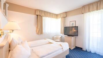 Een hotelkamer met een bed, een stoel, een televisie en een lamp.