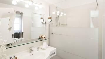 Un bagno moderno con box doccia in vetro, un mobile lavabo con specchio e un asciugacapelli sul ripiano.