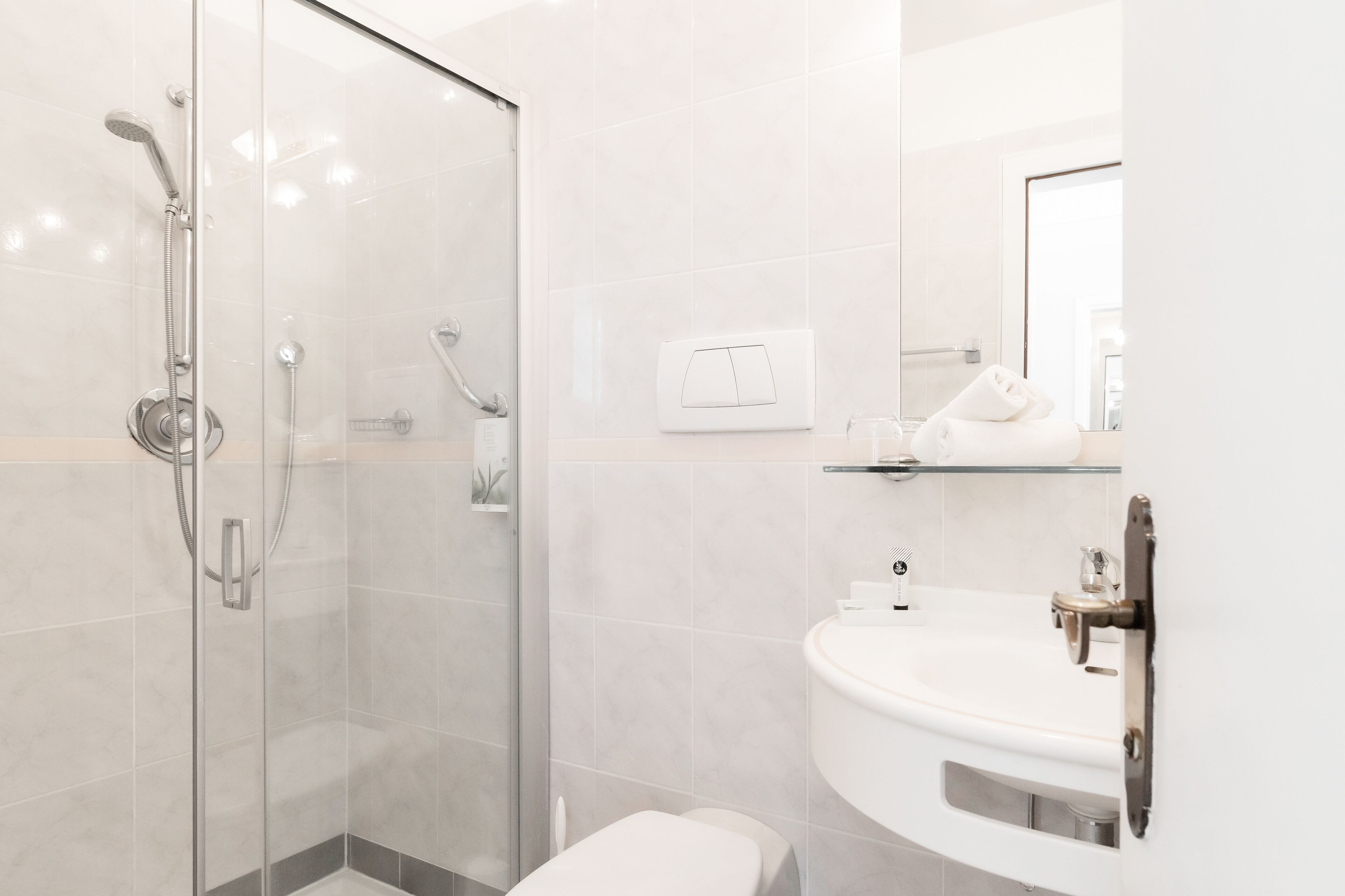 A modern bathroom with a glass shower enclosure, a white sink, and a mirror.