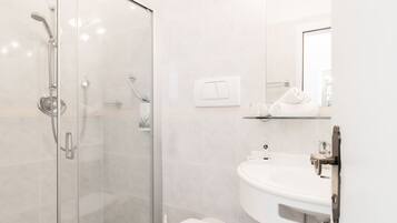 A modern bathroom with a glass shower enclosure, a white sink, and a mirror.