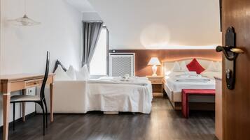 Een hotelkamer met een bed, een bureau, een stoel, een nachtkastje met een lamp en een kledingkast.
