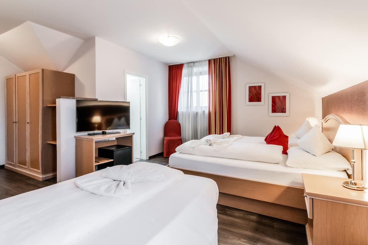 A hotel room with two beds, a TV, a wardrobe, and a desk.