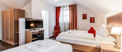 A hotel room with two beds, a TV, a wardrobe, and a desk.