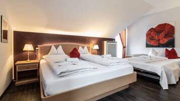 Camera d'albergo con un letto grande, due comodini con lampade, un quadro di un fiore rosso e una finestra con tende.