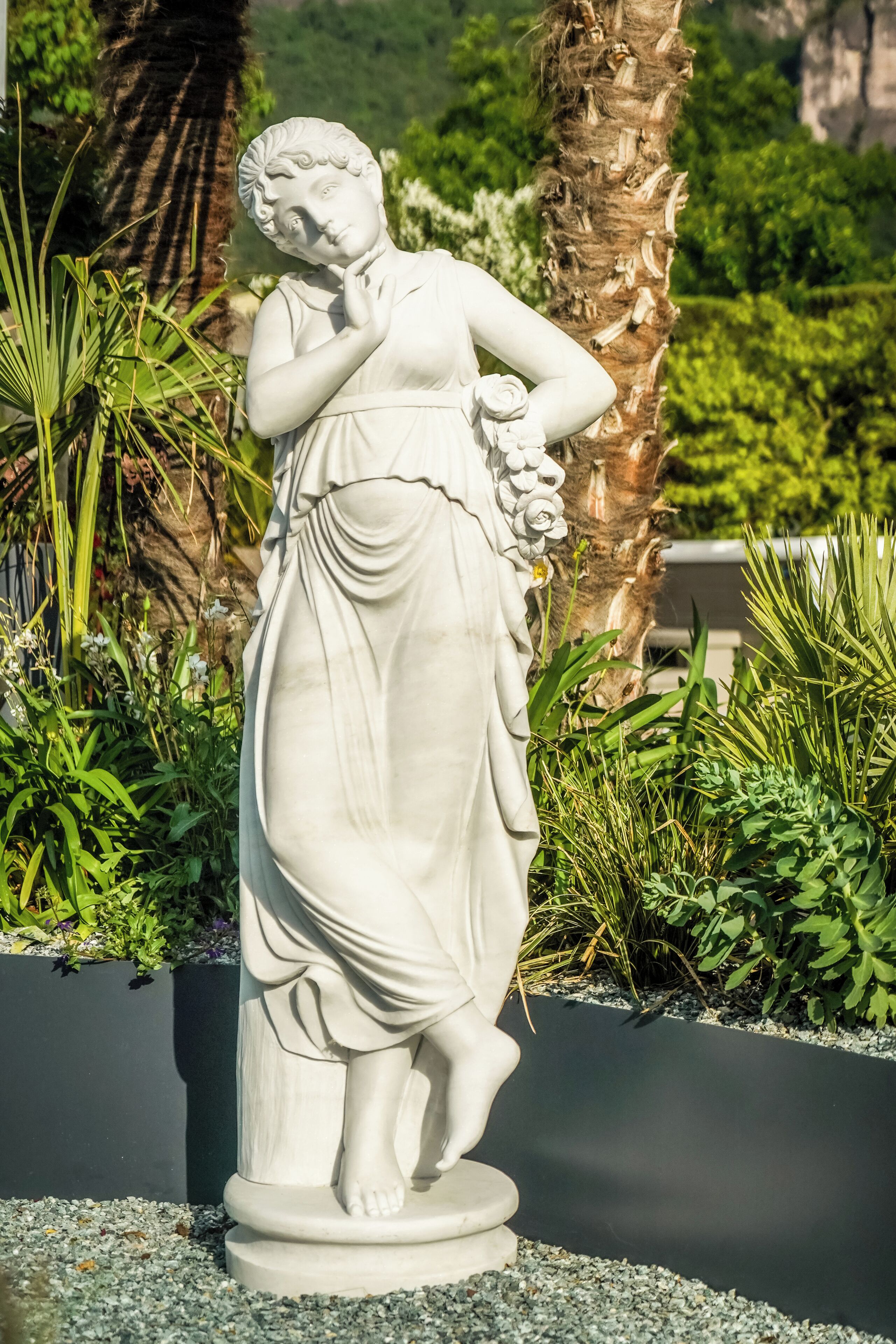 Una estatua blanca de una mujer en un jardín.