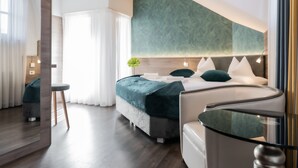 A modern hotel room with a bed, bedside tables, a mirror, and a view of the outdoors. - Hotel Villa Groff (Ora)