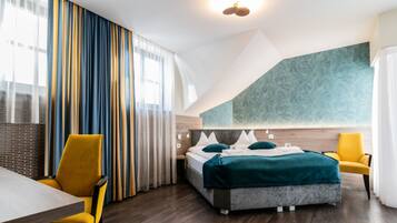 Una habitación de hotel moderna con una cama, dos sillones amarillos, una mesa y un ventanal con cortinas.